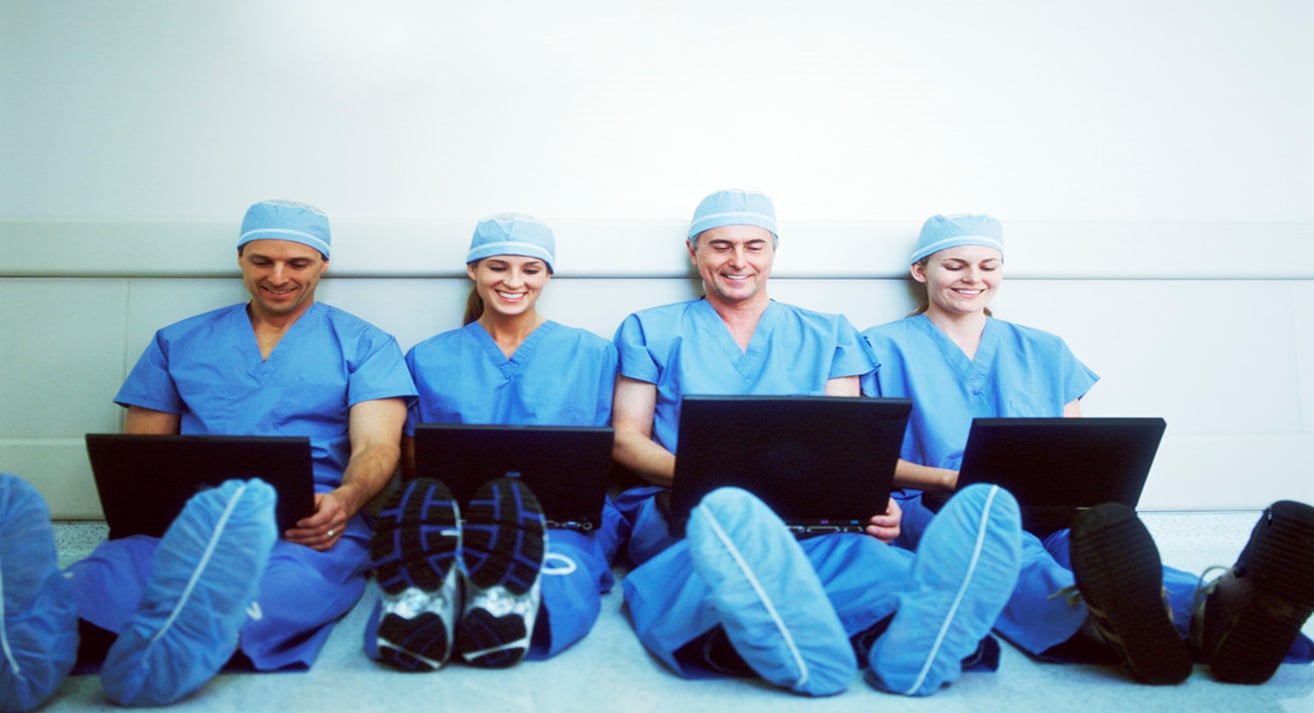 four medical professionals looking at laptops